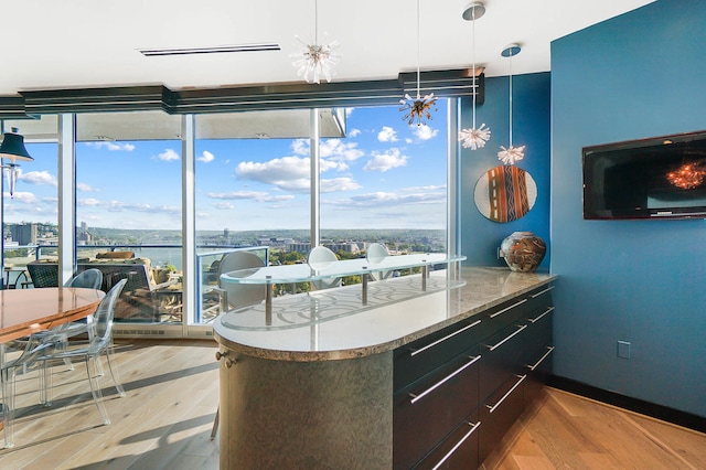 kitchen with pendant lighting, a notable chandelier, a water view, and light wood-type flooring