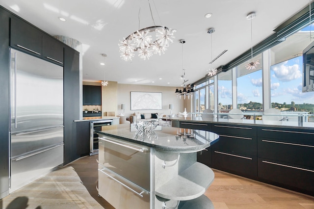 kitchen featuring hanging light fixtures, a kitchen island, light hardwood / wood-style floors, a notable chandelier, and built in refrigerator