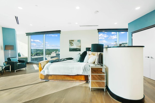 bedroom with light hardwood / wood-style floors, expansive windows, and multiple windows