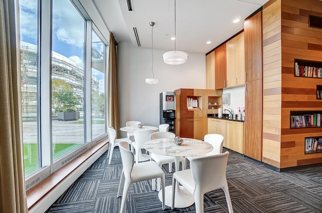 carpeted dining room with sink and wooden walls