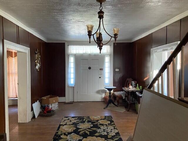 foyer with a textured ceiling, crown molding, light hardwood / wood-style floors, and a chandelier