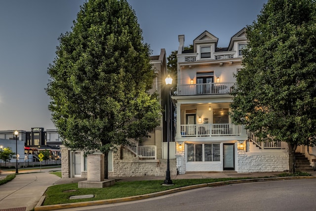 view of front of house featuring stairs, a balcony, and stone siding