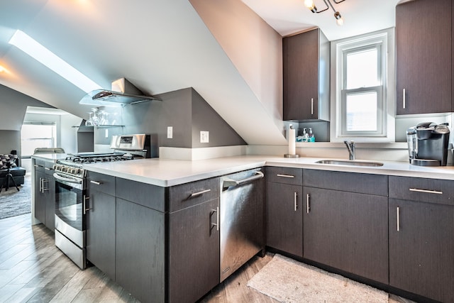 kitchen featuring light countertops, a sink, appliances with stainless steel finishes, and light wood-style floors