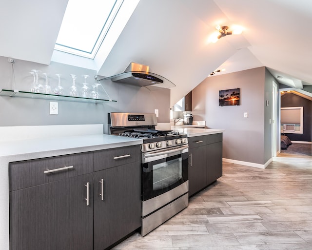 kitchen featuring gas range, light wood-type flooring, lofted ceiling with skylight, and range hood