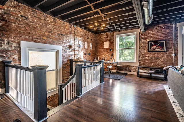 hall with dark wood-type flooring and brick wall