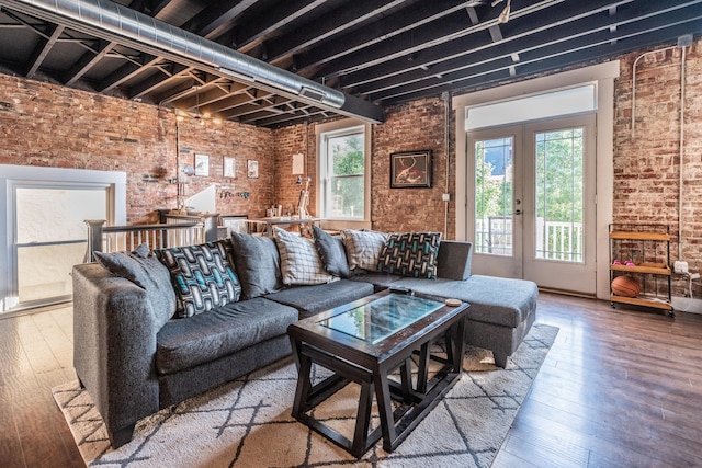 living room with brick wall, french doors, and hardwood / wood-style floors