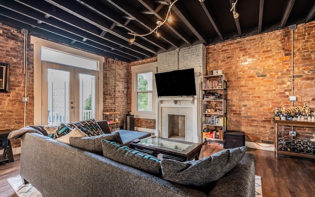 living room with wood-type flooring, french doors, and brick wall