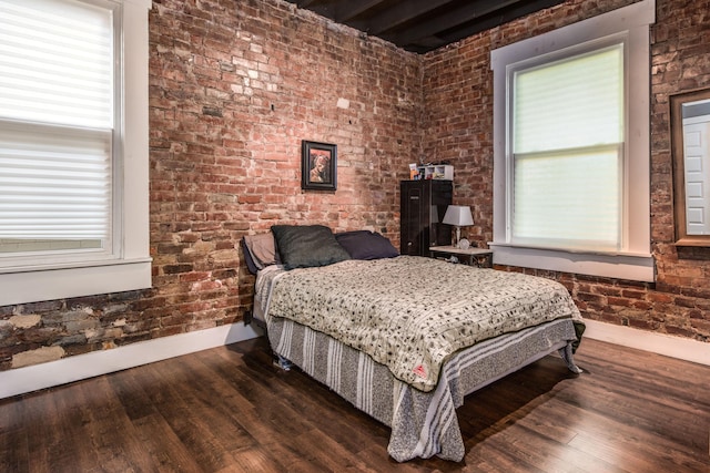 bedroom with wood-type flooring, multiple windows, and brick wall