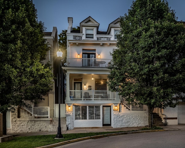 view of front of house featuring brick siding, stone siding, stairway, and a balcony