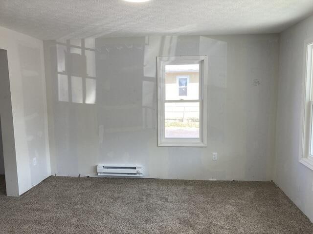 empty room with carpet floors, a baseboard radiator, and a textured ceiling