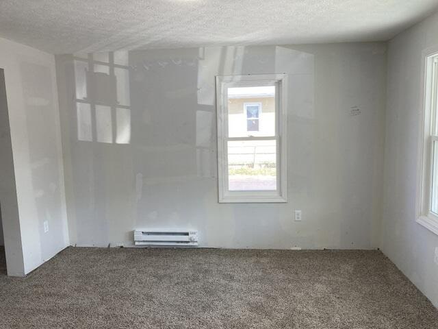 unfurnished room featuring carpet floors, a baseboard radiator, and a textured ceiling