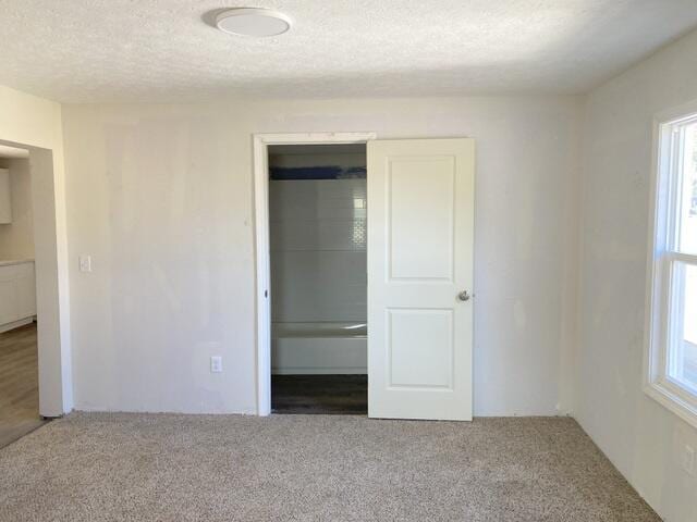 unfurnished bedroom with a textured ceiling, a closet, and carpet flooring