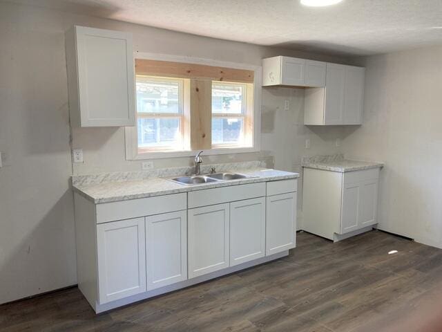 kitchen featuring a textured ceiling, white cabinetry, sink, and dark hardwood / wood-style flooring