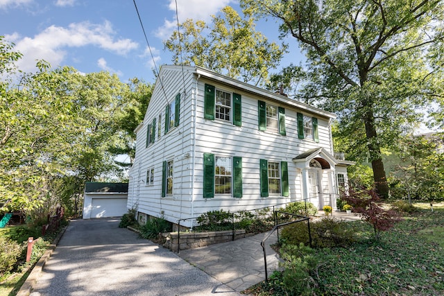 colonial home with a garage and an outbuilding