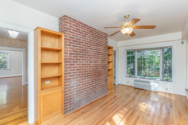 unfurnished room featuring light wood finished floors, a wall mounted air conditioner, a ceiling fan, and baseboards