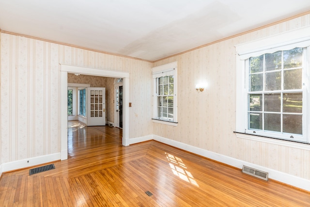 empty room with baseboards, visible vents, and wallpapered walls