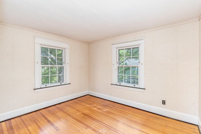 unfurnished room with wallpapered walls, baseboards, wood finished floors, and ornamental molding