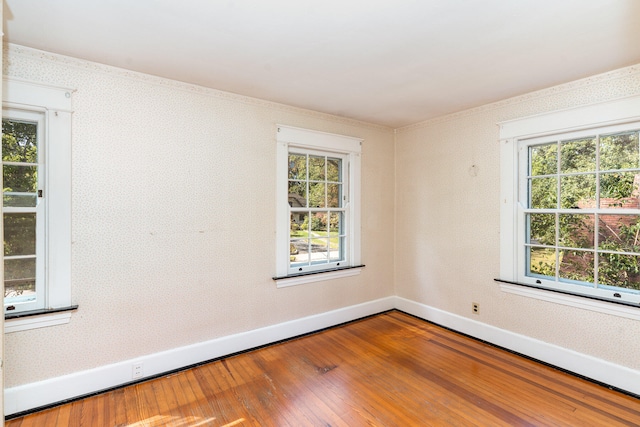 unfurnished room with wallpapered walls, baseboards, and wood finished floors