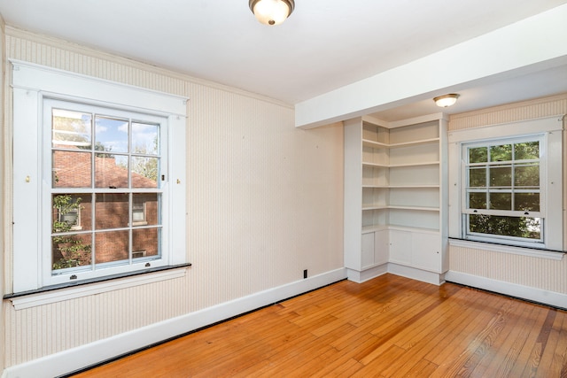 spare room featuring baseboards, plenty of natural light, wood finished floors, and wallpapered walls