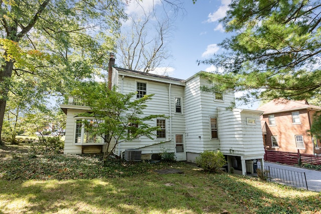 rear view of house featuring a lawn, fence, and cooling unit