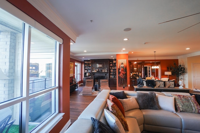 living room with a notable chandelier, a fireplace, crown molding, and dark hardwood / wood-style floors