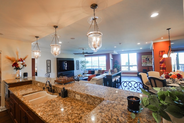 kitchen with light stone countertops, decorative light fixtures, sink, and wood-type flooring