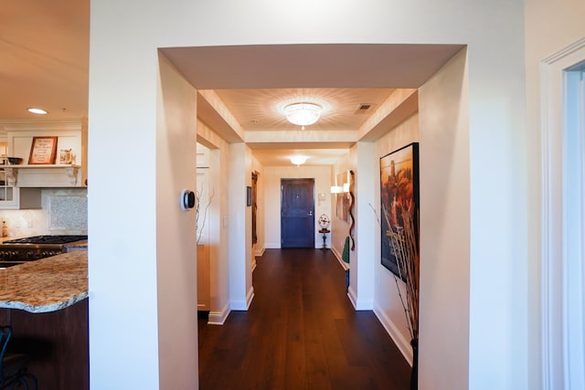 hallway featuring a raised ceiling and dark hardwood / wood-style flooring