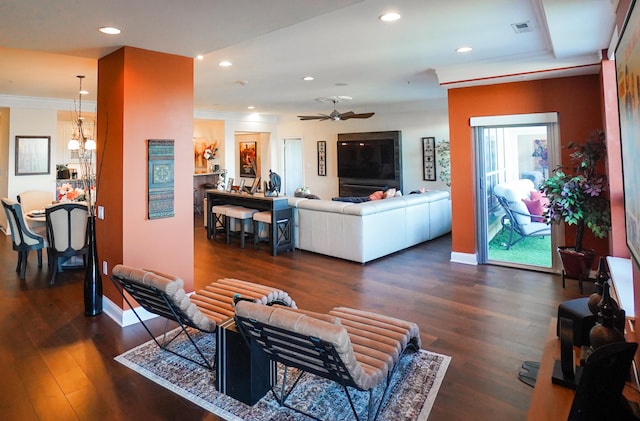 living room with ceiling fan with notable chandelier, crown molding, and dark hardwood / wood-style flooring