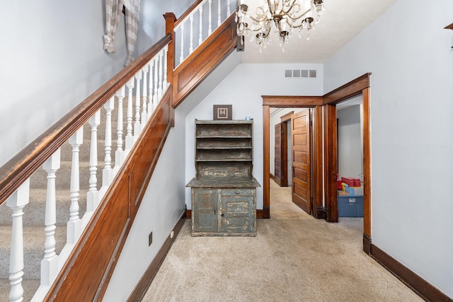 stairs with carpet flooring and a notable chandelier