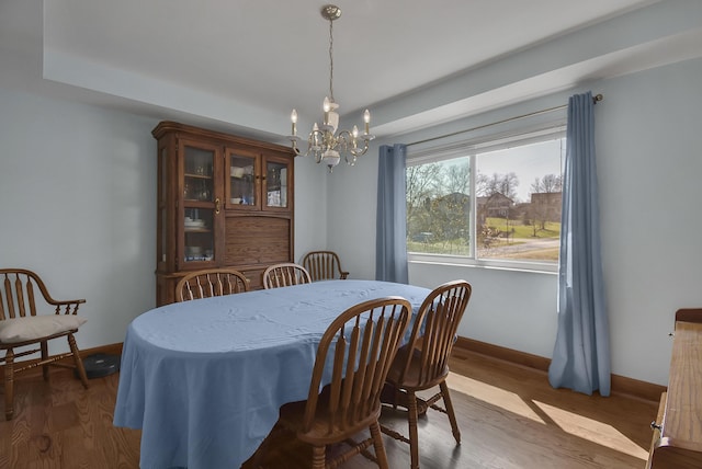 dining area with wood finished floors, baseboards, and a chandelier