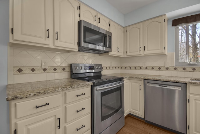 kitchen with tasteful backsplash, dark wood finished floors, appliances with stainless steel finishes, and light stone countertops