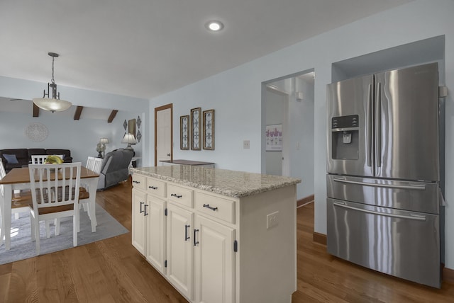 kitchen with dark wood-type flooring, light stone counters, stainless steel fridge with ice dispenser, and open floor plan