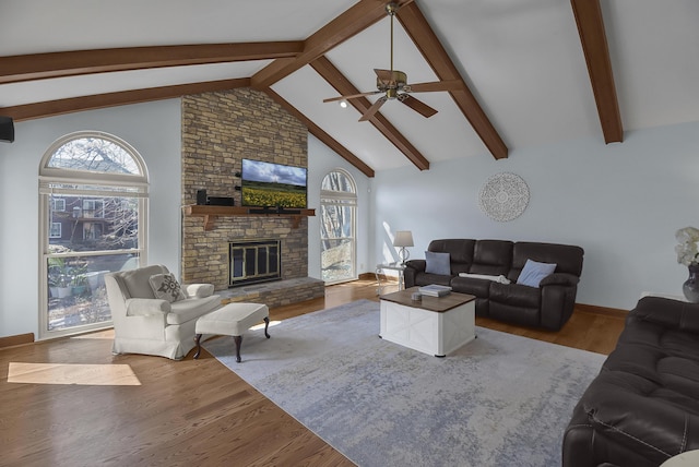 living room with beamed ceiling, high vaulted ceiling, a ceiling fan, wood finished floors, and a fireplace