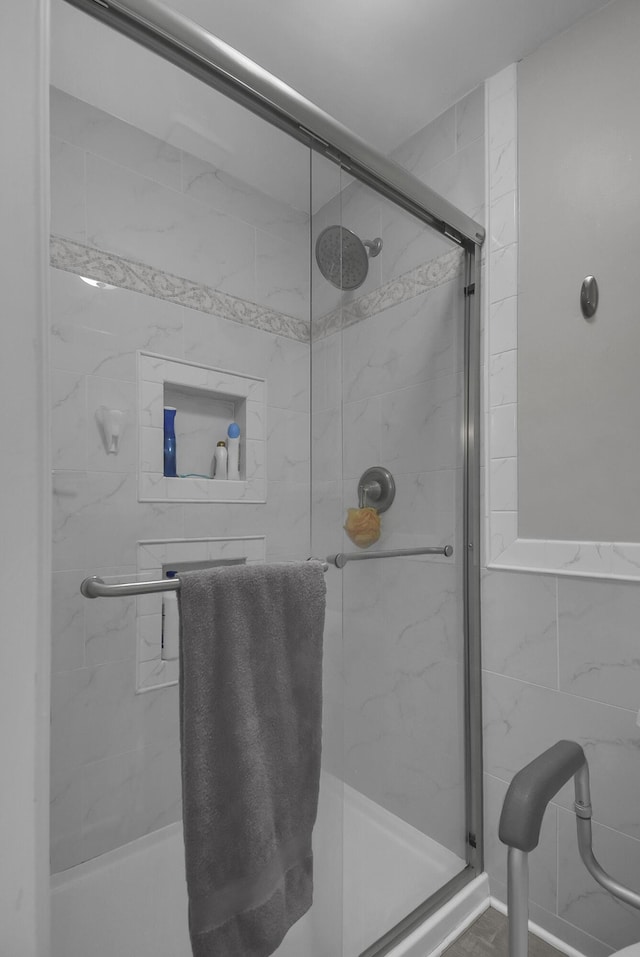 bathroom with a shower stall and tile walls