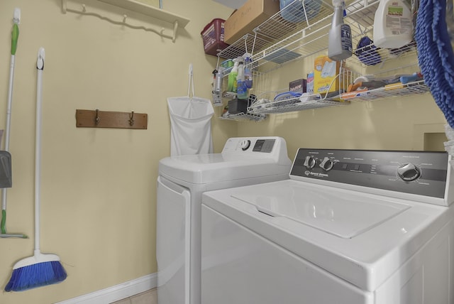 clothes washing area featuring baseboards, laundry area, and washing machine and clothes dryer