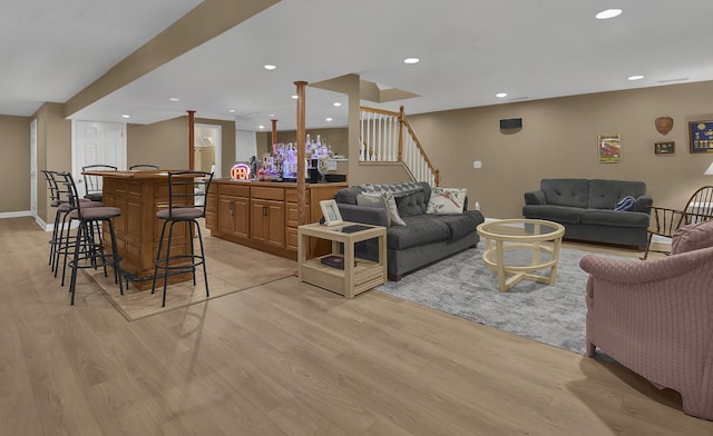 living room featuring baseboards, indoor bar, stairs, recessed lighting, and light wood-style flooring