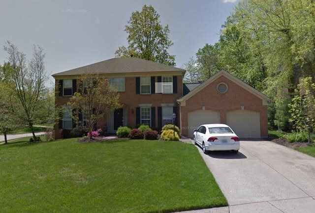 colonial home featuring driveway, an attached garage, and a front yard