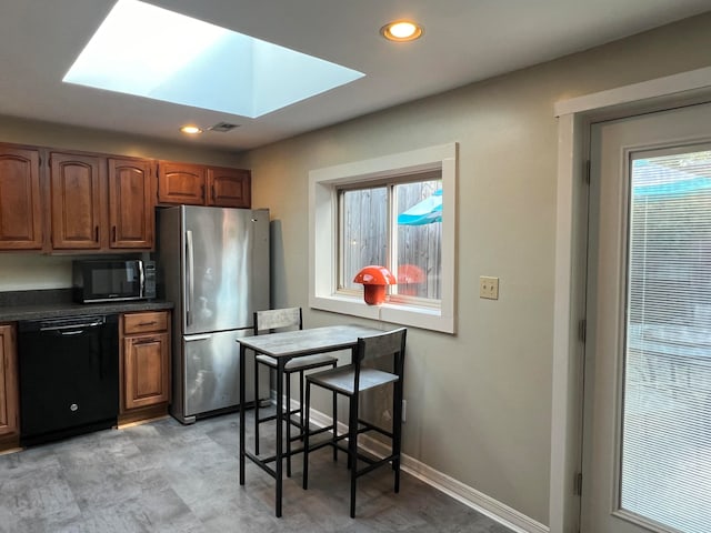 kitchen with a skylight, a healthy amount of sunlight, and black appliances