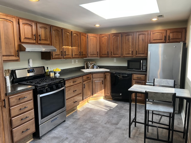 kitchen with sink, a kitchen breakfast bar, and black appliances