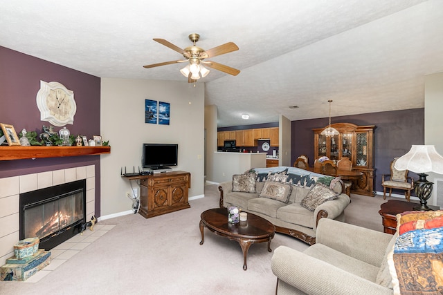 living room featuring a tiled fireplace, ceiling fan, a textured ceiling, lofted ceiling, and light colored carpet