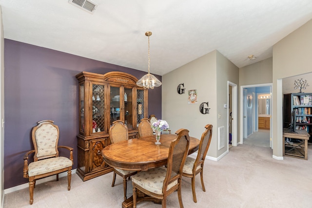 dining area with a chandelier, vaulted ceiling, and light carpet