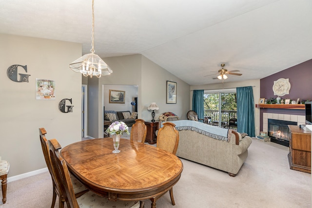 dining area featuring ceiling fan with notable chandelier, a tile fireplace, carpet flooring, and lofted ceiling