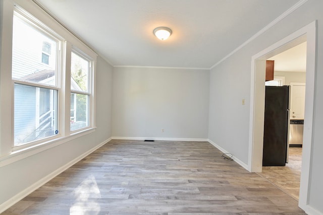 empty room with ornamental molding and light hardwood / wood-style floors