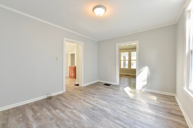 spare room with light hardwood / wood-style flooring, a textured ceiling, and crown molding