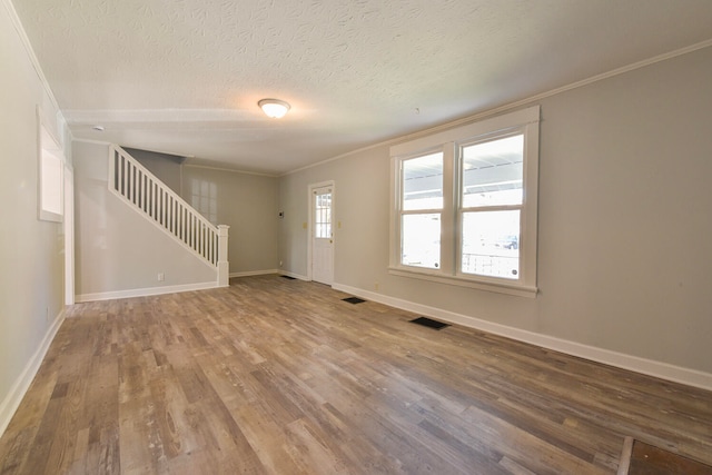 foyer entrance featuring crown molding, a textured ceiling, and hardwood / wood-style floors