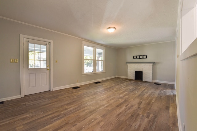 unfurnished living room with a fireplace, a textured ceiling, ornamental molding, and dark hardwood / wood-style floors