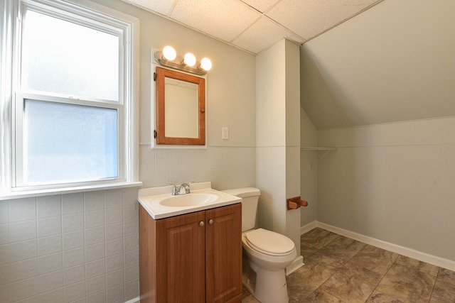 bathroom featuring a wealth of natural light, vanity, a drop ceiling, and toilet