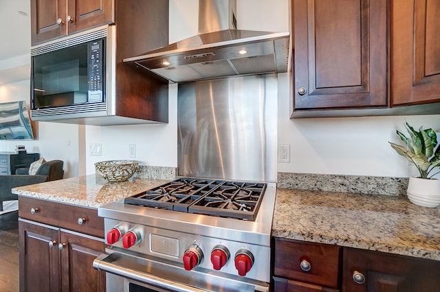 kitchen with light stone countertops, wall chimney range hood, black microwave, and stainless steel range