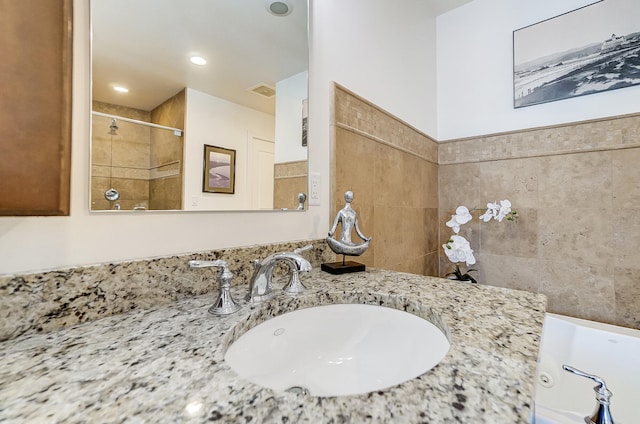 bathroom with vanity, independent shower and bath, and tile walls