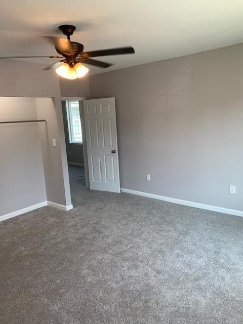 unfurnished room featuring dark colored carpet and ceiling fan